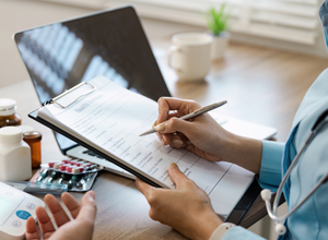 Photo of medical professional with laptop and clipboard